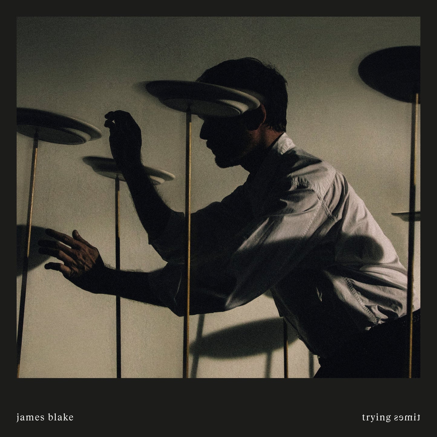 James Blake album cover: man with floating plates, muted tones.