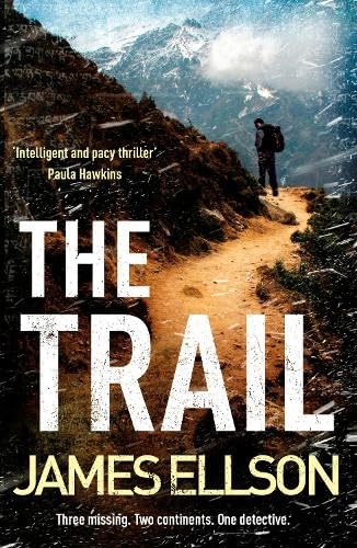 A hiker walks along a mountain trail under snowy, overcast skies.