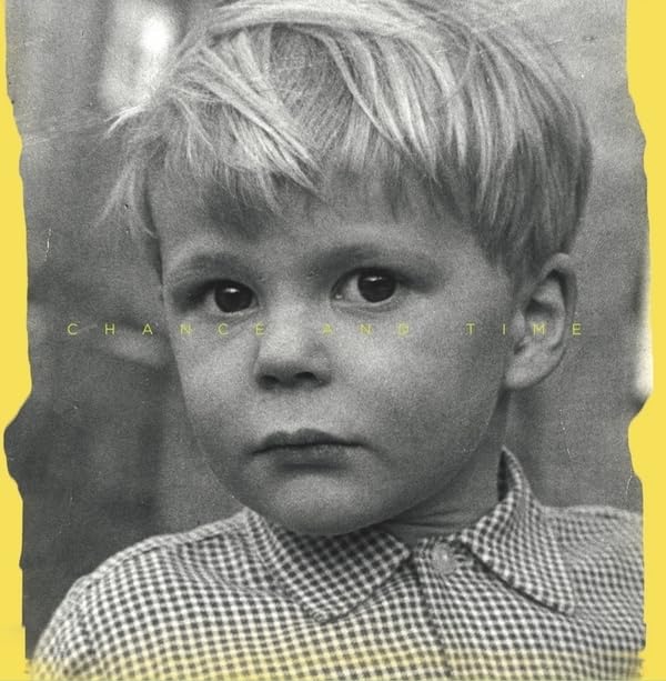 Black and white portrait of a young boy wearing a checkered shirt on yellow background.