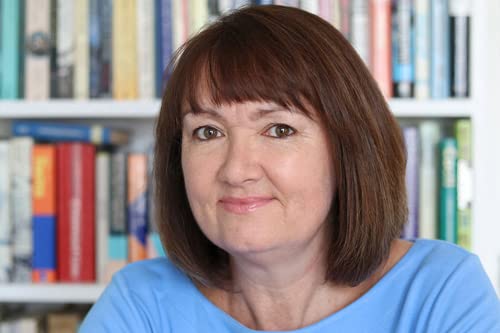 Headshot of author with brown hair, smiling, bookshelves in background.