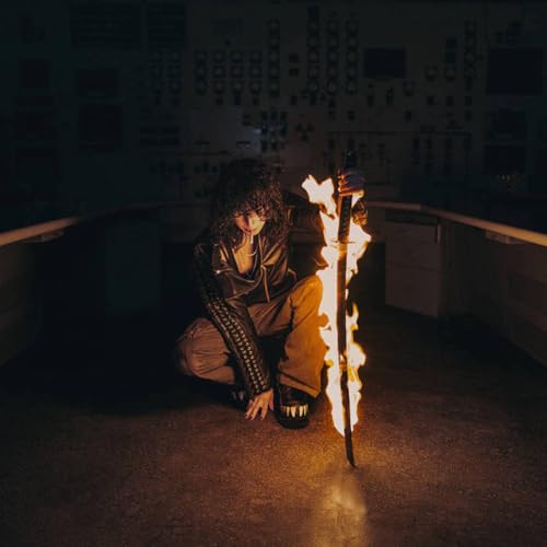 A person with curly hair crouches holding a flaming sword in a dark room.