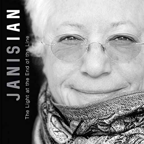 Black and white portrait of Janis Ian wearing round glasses, smiling gently.