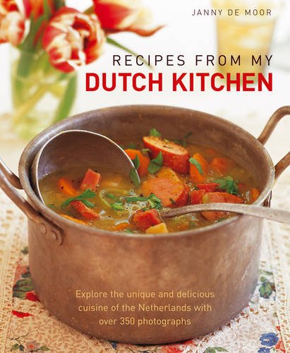 A copper pot of vegetable soup sits on a floral tablecloth with tulips nearby.