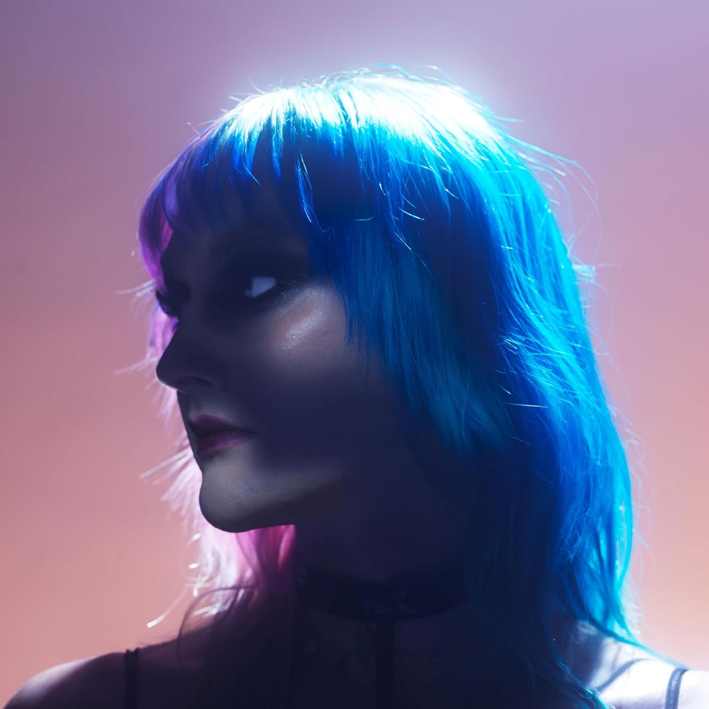 Woman with bright blue hair in a pink and purple light.