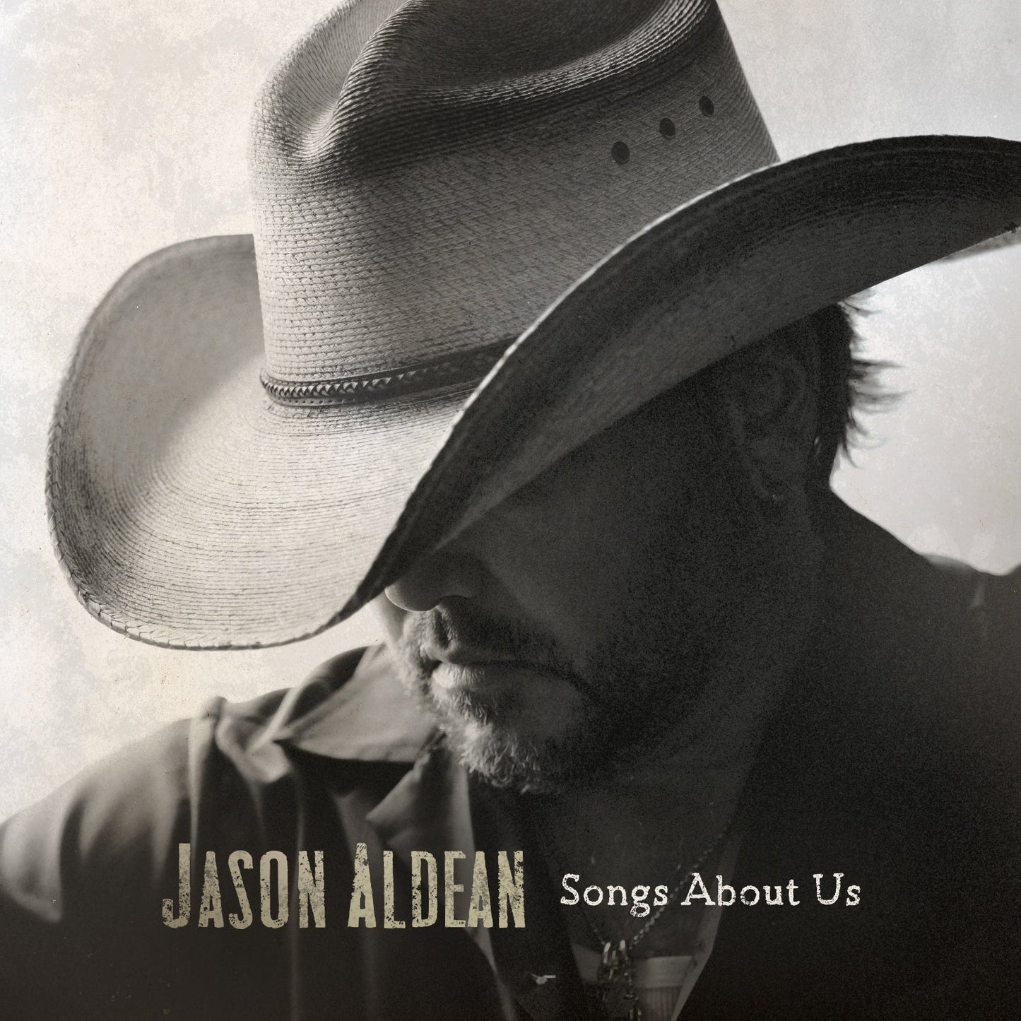 Black and white portrait of Jason Aldean wearing a cowboy hat covering his eyes.