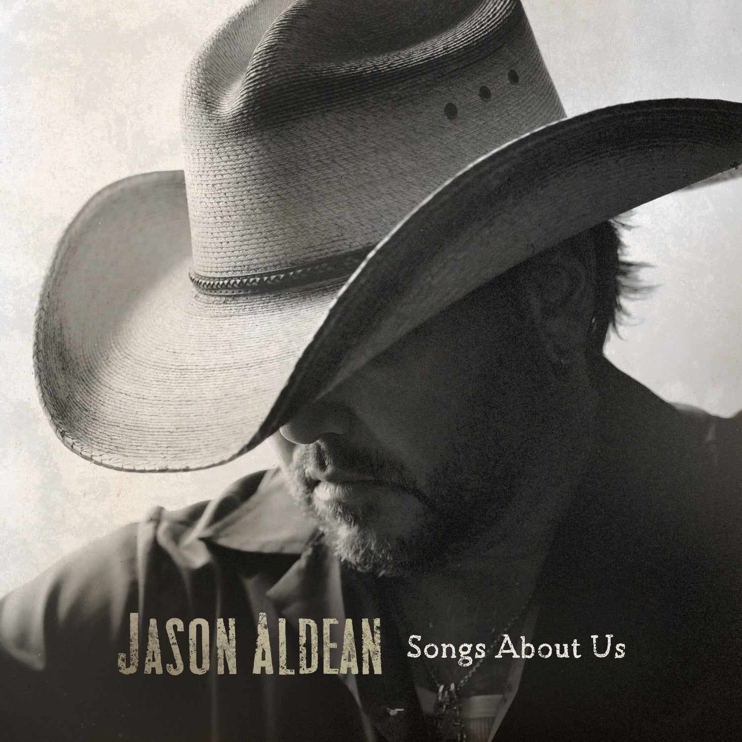Black and white portrait of Jason Aldean wearing a cowboy hat covering his eyes.