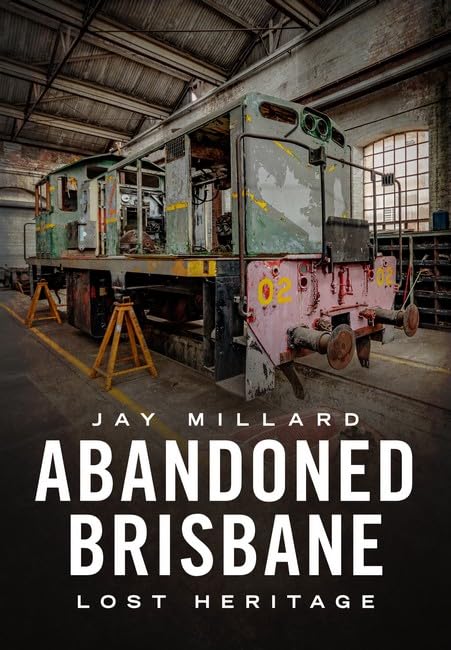 Dilapidated locomotive inside a large, decaying industrial building.
