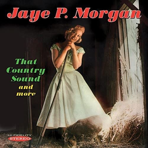 Jaye P. Morgan in a light dress leaning on a rake in a barn.
