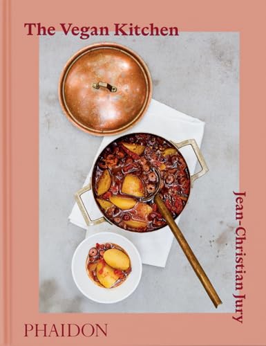 A copper pot of stew and a small bowl of potatoes on a table.