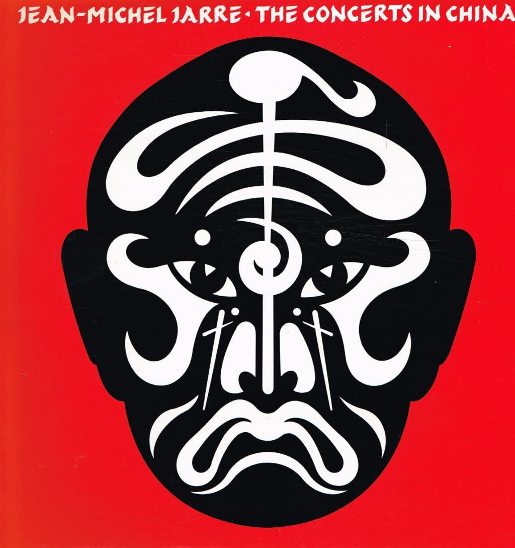 Red album cover with black and white face design and white text at top.