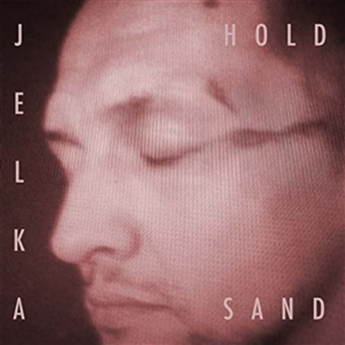 Close-up of a person’s face with text: “Jelka - Hold Sand.”