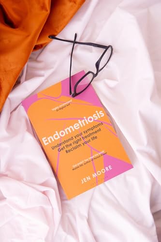 A book titled Endometriosis with black glasses resting on top, placed on white fabric.