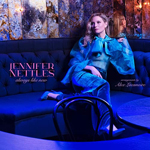 Woman in blue outfit sitting on a couch with a chair in front.