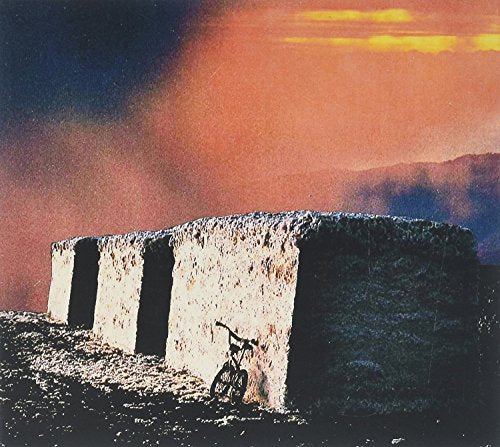 Album cover with a bicycle leaning against a stone wall at sunset.