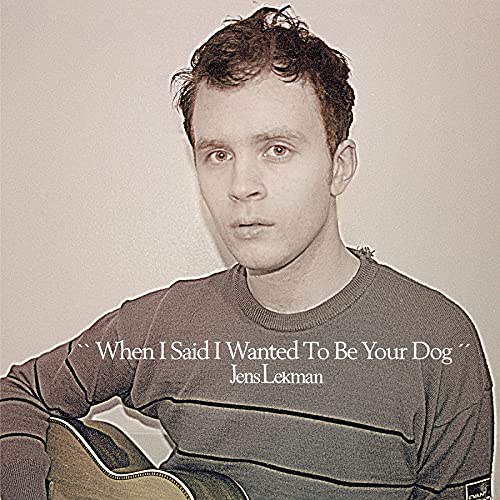 Sepia-toned portrait of Jens Lekman holding an acoustic guitar against a plain background.