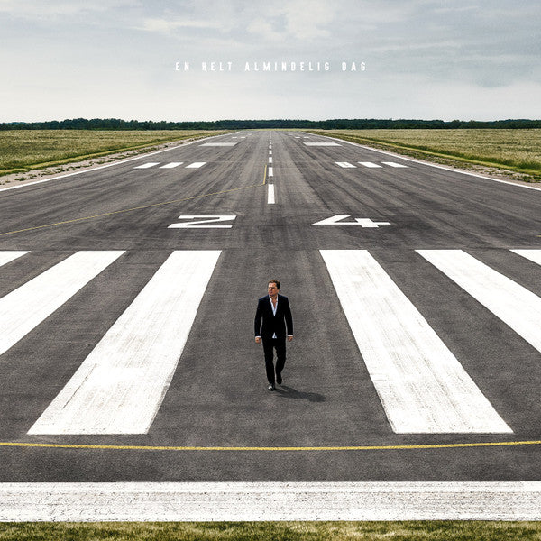 Man in suit walking on airport runway crossing lines.