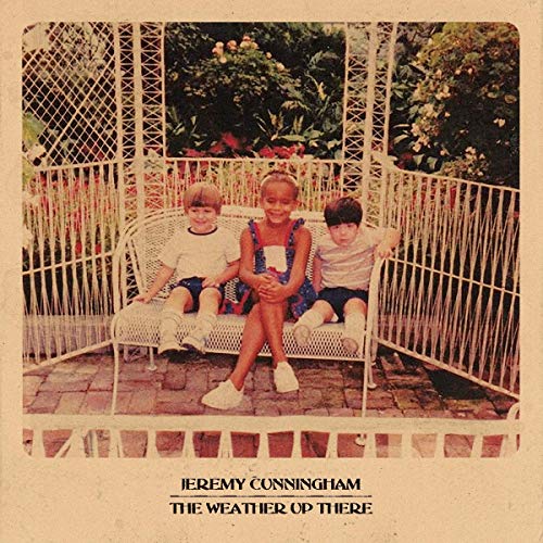 Album cover with three children sitting on a white wicker bench in a garden.