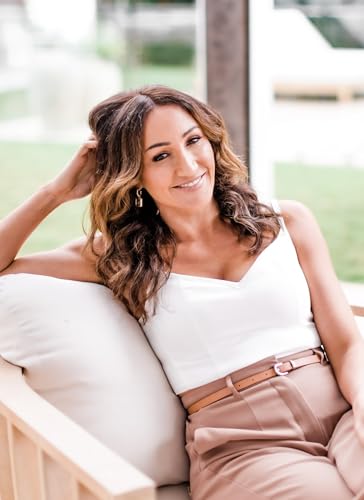 Woman with wavy brown hair smiling, resting on a cushioned outdoor seat.