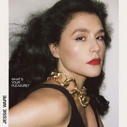 Close-up portrait of Jessie Ware wearing a chunky gold chain necklace and red lipstick.