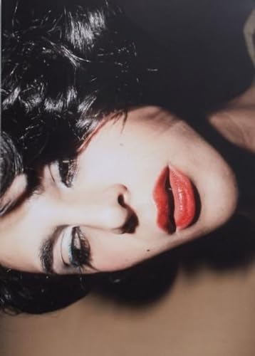 Close-up portrait of a person with dark curly hair and red lips.