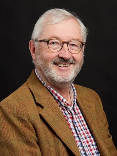 Headshot of a smiling older man with grey hair, glasses, and a tweed jacket.