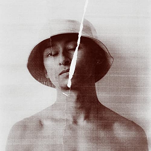 Sepia-toned portrait of a person wearing a wide-brimmed hat, eyes closed.