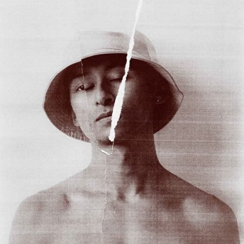 Sepia-toned portrait of a person wearing a wide-brimmed hat.