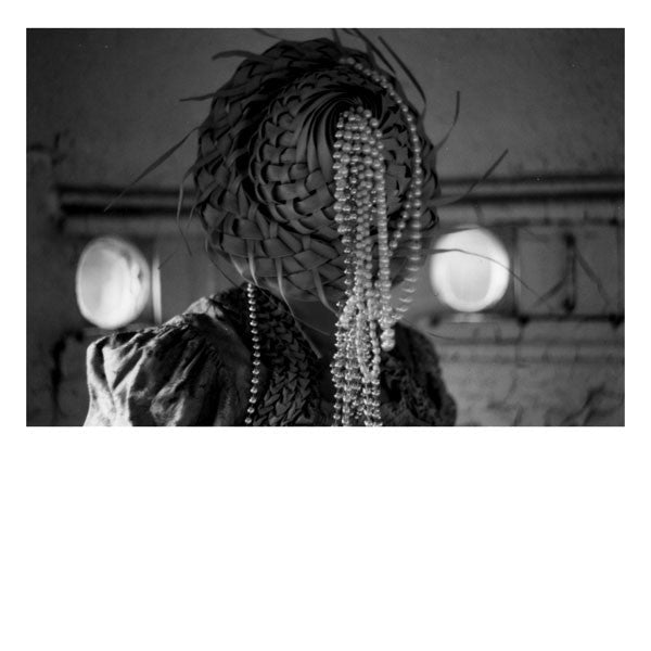 Black and white photo of a person with beaded hair and lace.