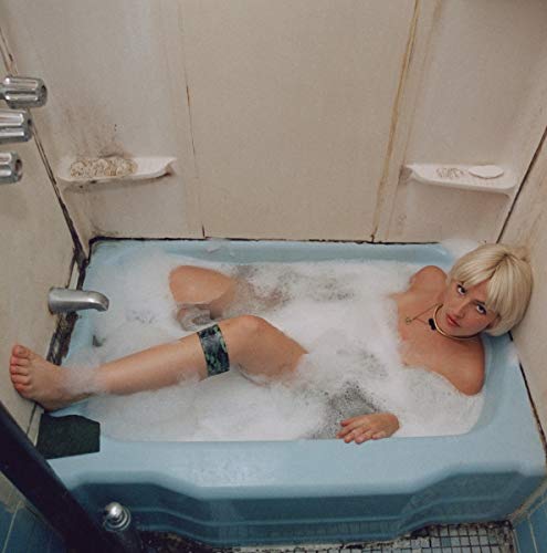 Woman with short blonde hair in a bubbly blue bathtub.