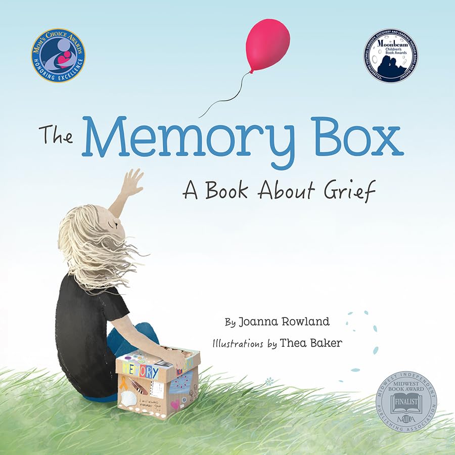 A child sits in grass reaching for a red balloon next to a memory box.