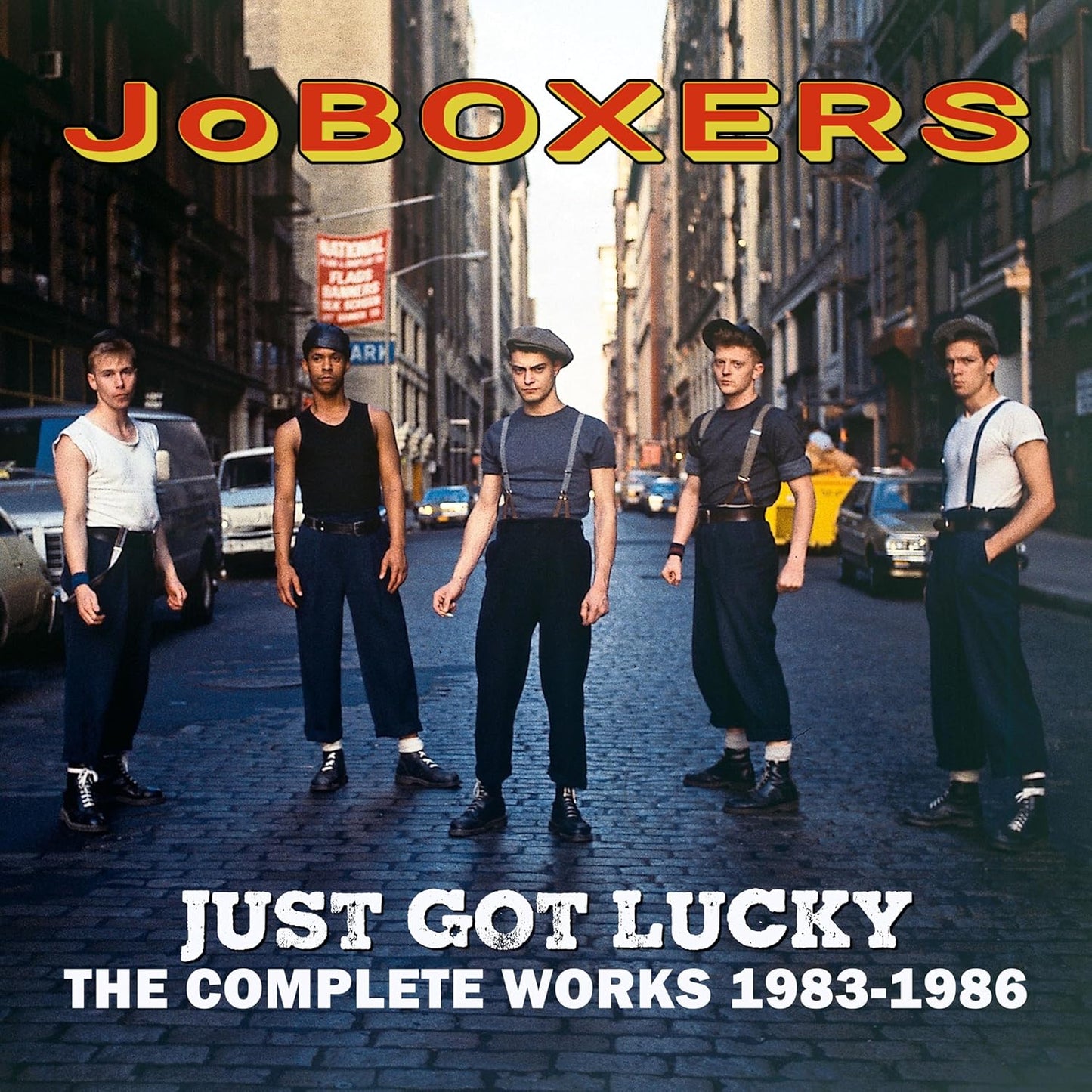 Five men in vintage workwear standing on a cobblestone city street.
