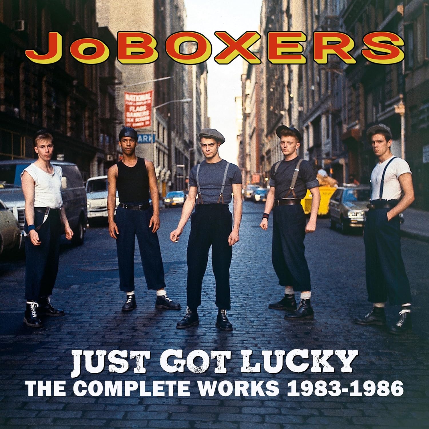 Five men in vintage workwear standing on a cobblestone city street.