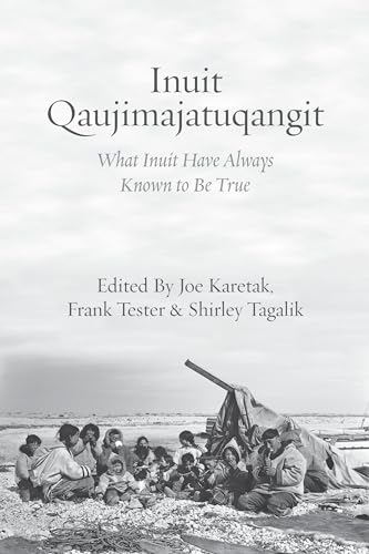 Black and white photo of Inuit people sitting on ground near a tent.