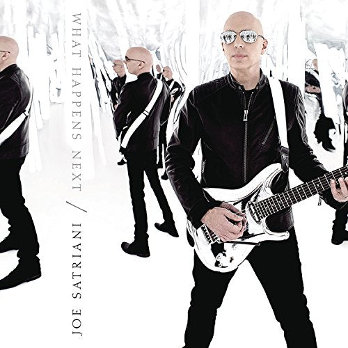 Joe Satriani in black suit with guitar, mirrored reflections background.