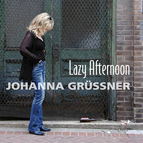 Woman with blonde hair stands by a green door, CD cover.