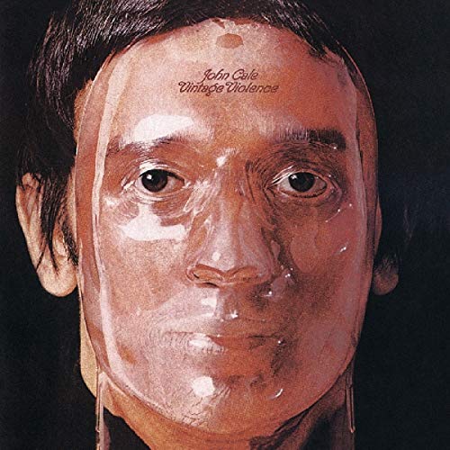 Album cover with a man's face, partially covered in plastic wrap, against a black background.