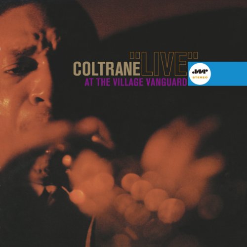 John Coltrane playing saxophone in a dark, warm-toned live performance photograph.