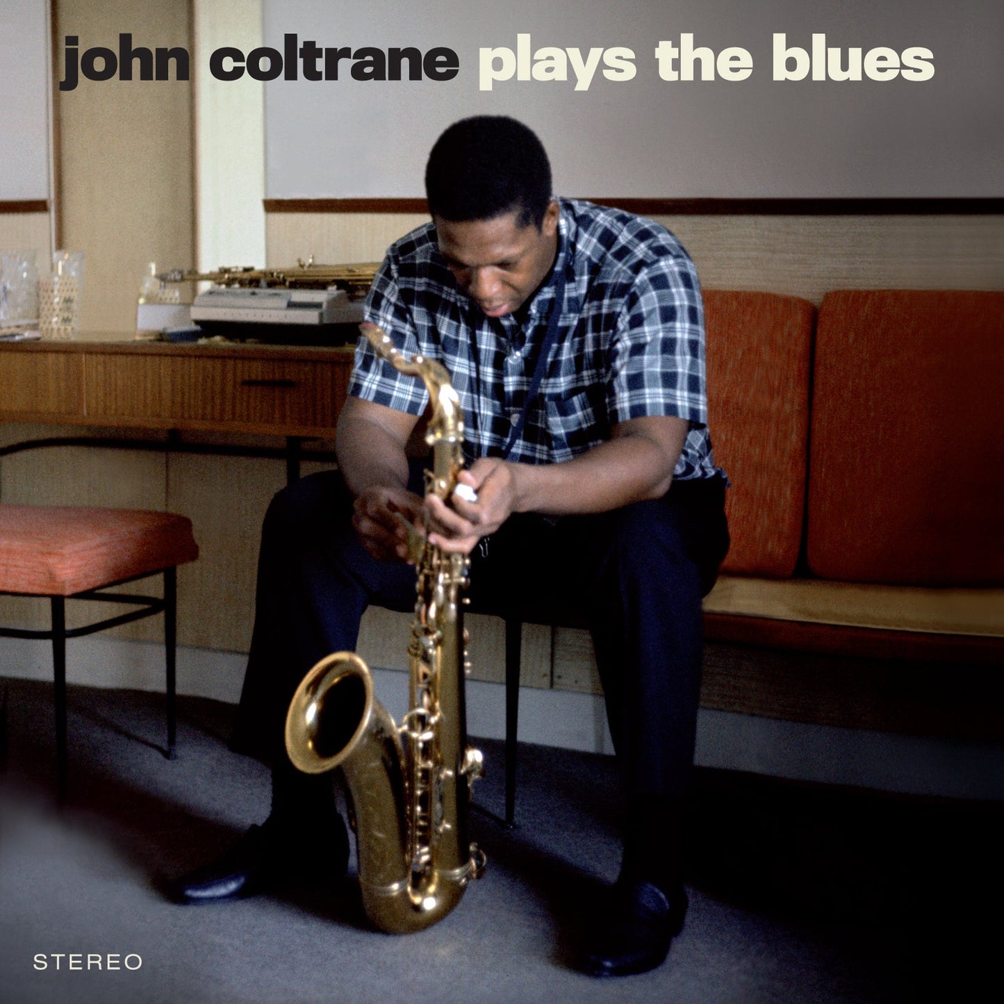 John Coltrane sitting and holding a saxophone, album cover for Plays The Blues.