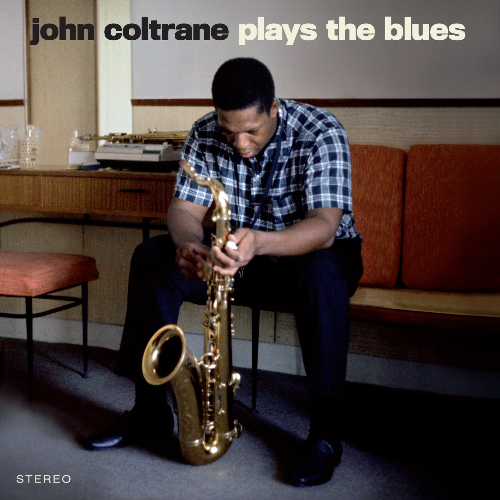 John Coltrane sitting and holding a saxophone, album cover for Plays The Blues.