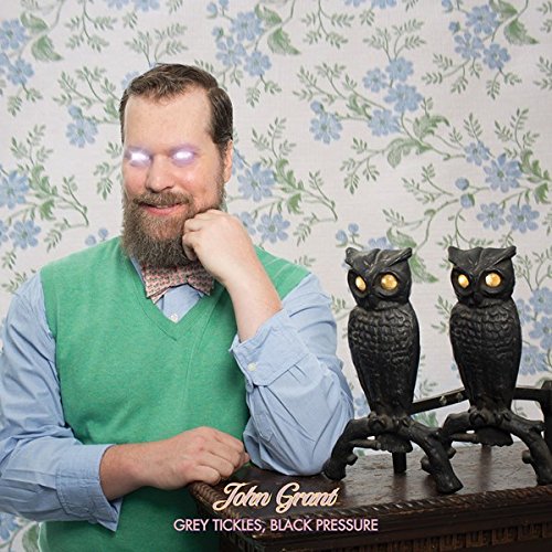 John Grant album cover with man, owls, and floral wallpaper.