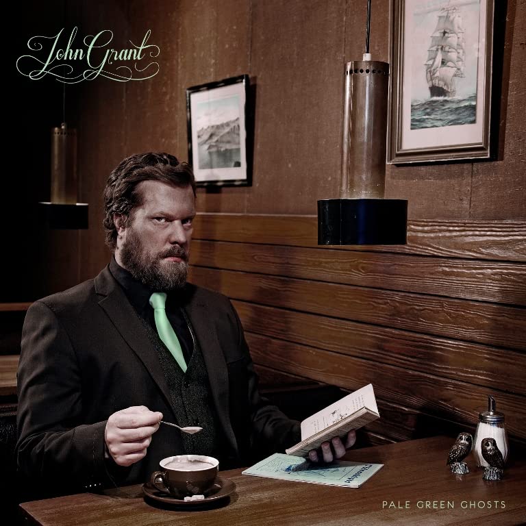 John Grant album cover: man with beard at a table, reading.