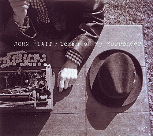 Black and white album cover featuring a man with a typewriter and hat.