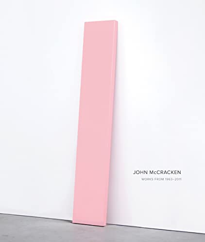 Pink rectangular sculpture leans against a white wall, book cover visible.