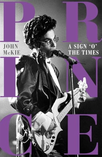 Black and white photo of Prince singing into a microphone while playing an electric guitar.