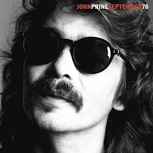 Black and white portrait of John Prine wearing sunglasses, album cover.