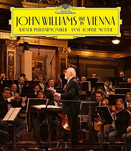 John Williams conducting the Vienna Philharmonic orchestra in a concert hall.