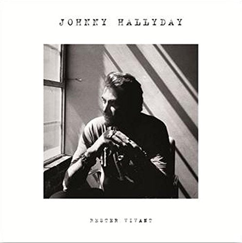 Black and white image of a man sitting by a window, holding a guitar.