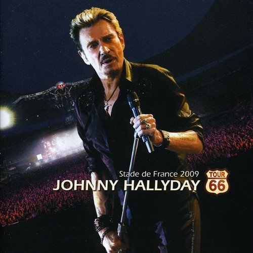 Johnny Hallyday singing into a microphone on stage before a crowd.