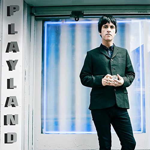 Johnny Marr portrait in front of a blue and white “Playland” sign.