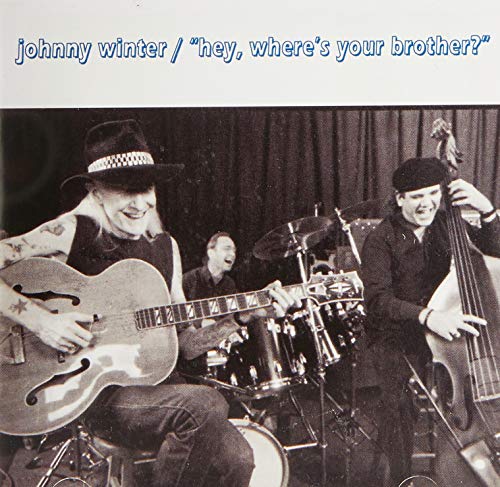 Black and white photo of Johnny Winter playing guitar with bandmates.